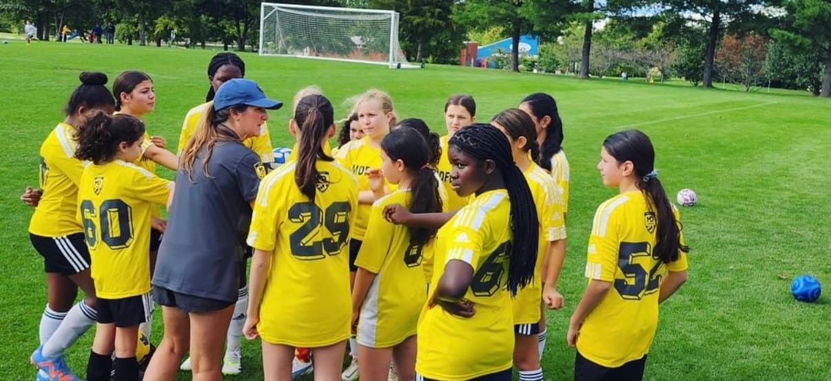 MD Fusion girls team gathered in a huddle on the field