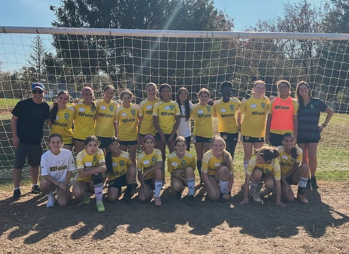 An MD Fusion girls team gathered together at the goal after a match